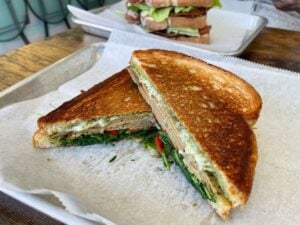 Vegan Turkey pesto sandwich with roasted red peppers and arugula.