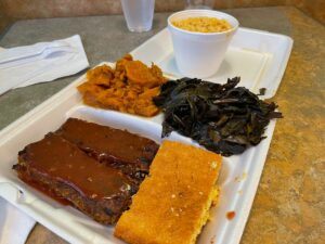 Take out tray of vegan mac and cheese, vegan ribs, sweet potatoes, collard greens and corn bread.